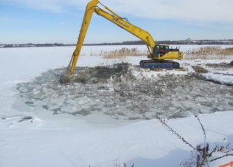 Ice must be cleared with an excavator as work continues rebuilding the southwest shoreline.