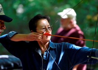 Attendees not only observe, but also have the chance to try out various activities with coaching by skilled practitioners.  Mimi Mark, from Tully, tries archery.