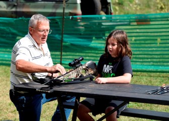 Josh O’Connor (right), from Syracuse, learns how a crossbow works from Lance Robson of the Falcon Sportsmen Club in Auburn.  Robson is also Chair of the New York State Fish and Wildlife Management Board.