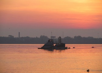 A hydraulic capping barge on Onondaga Lake near sunrise.