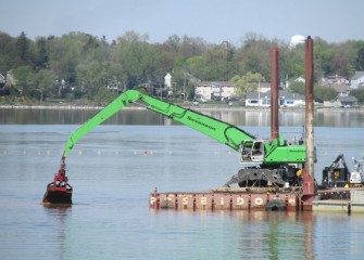 Mechanical capping now takes place in several locations at the same time. The Onondaga Lake Yacht Club is in the distance behind this barge.