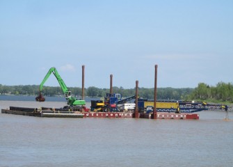 A telescoping radial stacking conveyor, or telestacker (right), is installed on a barge to assist in capping operations.