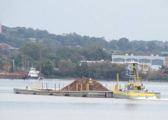 A tugboat pushes a delivery of material for mechanical capping.