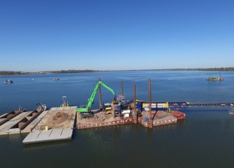 A material handler loads capping material into a hopper leading to the telestacker.