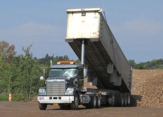 A load of coarse gravel arrives to a capping support area.