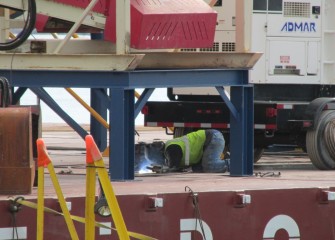 A welder works on an additional barge being assembled for capping operations.