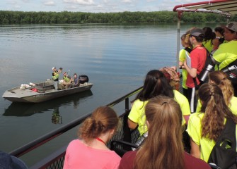 A SUNY-ESF research boat pulls up alongside the Emita II to show students fish just caught in Onondaga Lake.