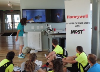 Honeywell Educator Sue Potrikus uses a special projector to show living microscopic zooplankton and phytoplankton in a sample of water just taken from the lake.