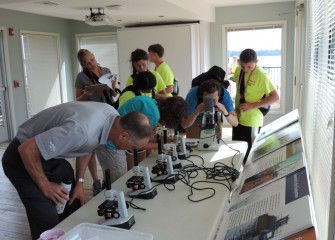 John McAuliffe (left) participates with students as they observe living microorganisms from the lake.