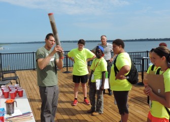 Mike Conese, Environmental Engineer at Anchor QEA, shows students a sample cross-section of a lake bottom cap before students have an opportunity to construct a sample cap on their own.
