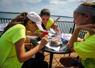 Students use sand, granulated activated carbon, gravel, and siderite, a mineral, to construct sample caps.