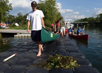 Nick Glaza (left) and his father Ed, of Skaneateles, carry their canoe out to launch, passing by sample water chestnut plants on the dock.