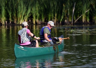 Anita Freezman and son Ian (right), from Syracuse, keep an eye out for stray water chestnut plants near shore.