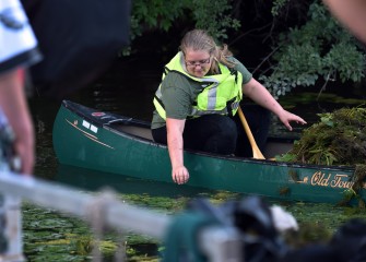 Rose Boerschlein from Ontario, NY, reaches to remove a water chestnut plant. Removing by hand is relatively easy, and is a safe and effective method for controlling the invasive plant.