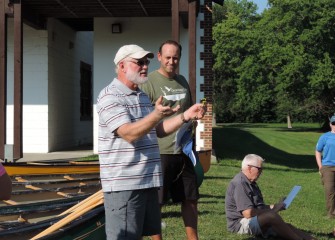 Joe McMullen (left), habitat expert with OBG, shows volunteers a sample water chestnut plant (Trapa natans). Waterproof cards with information about the invasive plant are distributed.