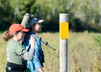 Rachel Elder, M.D. (left), and Alison Kocek, President of Onondaga Audubon Society, spot birds in grassland areas near the shoreline.