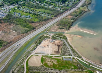 Workers drive trucks on equipment mats extending into the lake (above right) to place topsoil, creating a habitat layer for plantings.