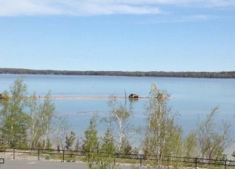 The shallow depth requires workers to access  the area from shore. Equipment can be seen placing topsoil from the Onondaga County West Shore Trail.