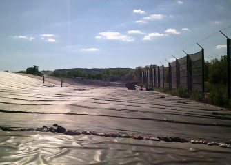 Installation and sealing of the geomembrane, or cover liner, continues.