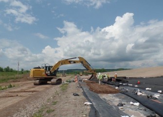 Workers begin to fill channels around the perimeter with soil.