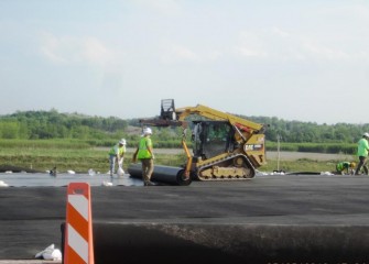 Workers roll out the polyethylene liner. Sheets will be sealed together to create a seamless cover.