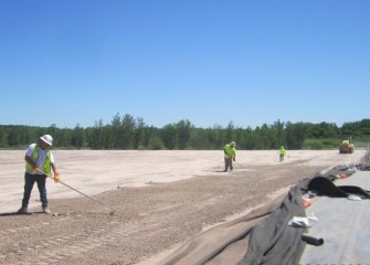 The surface of the leveling layer is raked by hand before cushion and liner placement.