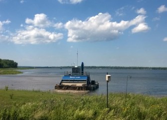 The hydraulic capping barge places topsoil near the Onondaga Lake Visitors Center. A bird box for Tree Swallows installed by the Onondaga Lake Conservation Corps is visible in the foreground.