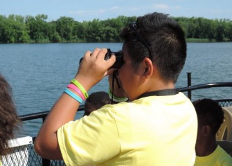 Rawri Da, from the Syracuse City School District, uses binoculars to spot birds in the water and along the shoreline.