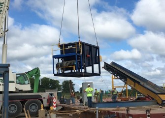 A section of the telestacker is hoisted off a barge.