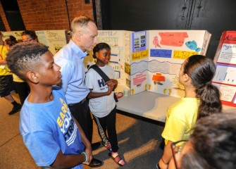 Honeywell Syracuse Program Director John McAuliffe listens to students describe their work during the poster session on Honeywell Discovery Day.