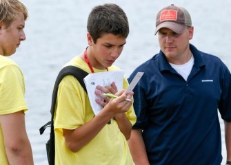 Alex Williams, from Bishop Grimes Junior/Senior High School, reads a pH test strip, recording observations after.