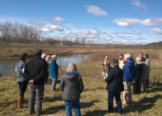 Members of the Garden Center Association of Central New York gather at Nine Mile Creek to plant an American sycamore tree.