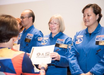 Colleen O’Connor from Roxboro Road Middle School receives a certificate and other materials during a graduation ceremony at Honeywell Educators at Space Academy.