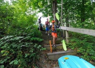 Grant Clift, age 8, from Baldwinsville, carries kayak paddles down to the creek shoreline.