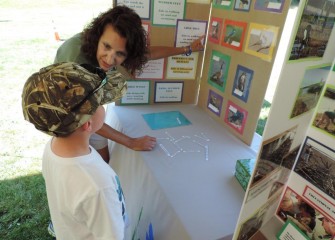 Sue Potrikus, coordinator for the Onondaga Lake Conservation Corps, works on a bird matching game with a visitor to her booth.