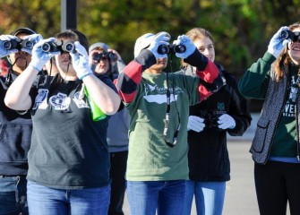 Members of the Binghamton University chapter of Alpha Phi Omega, a national coeducational service organization, observe birds in nearby trees.