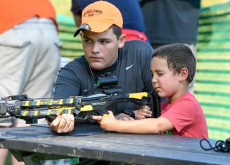 Fifteen-year-old New York Crossbow Coalition volunteer Tanner Hayes, of Hannibal, teaches 5-year-old Gabriel Rodriguez, of Clay, to use a crossbow.