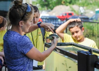 Scientist Anne Burnham shows students a Pumpkinseed and other fish caught in Onondaga Lake.