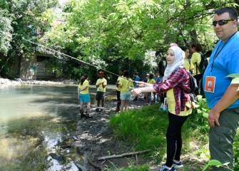 Student Ryanne Kanaan, from Jamesville-DeWitt Central School District, tosses a line in the water to try to catch a fish with help from Counselor Thomas Butler.