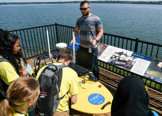 Honeywell Summer Science students learn about the Z-boat, a high tech remote-controlled boat which uses GPS and sonar to record data about the lake bottom.