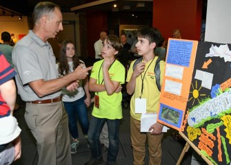 Students Symeon Barrett (center) and Peter Santoro (right) discuss their poster about channelizing Onondaga Creek and how it changed the creek ecosystem.