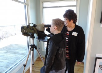 Michele Neligan, a former Onondaga Audubon board member and a photographer exhibiting at the event, helps 10-year-old Ethan Jackson, of Elbridge, New York, use a scope to identify a red-breasted merganser.