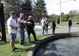 Onondaga County 3rd District Legislator Tim Burtis (second from left), from Brewerton, feeds one-year-old Brown Trout with son Alex (left).