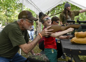 Aedan Hanifan, of Syracuse, tries air rifle with help from Jim Van Ben Coten of the Syracuse Rod & Gun Club. In the background, Luke Foster Springett, of Clay, is instructed by Eoin Holmes, of Syracuse.
