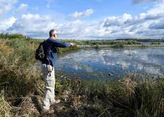 A seed bag tossed by Joe Hansen, of Liverpool, splashes into wetlands along the southwest shoreline.