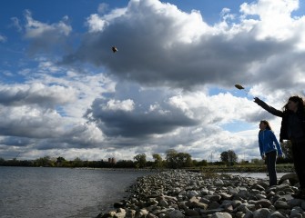 From a rock berm, sisters Evie (left) and Autumn Keefe, of Syracuse, throw seed bags into shallow water nearby. The target depth for pickerelweed seed bags is 6 inches to 2 feet of water.